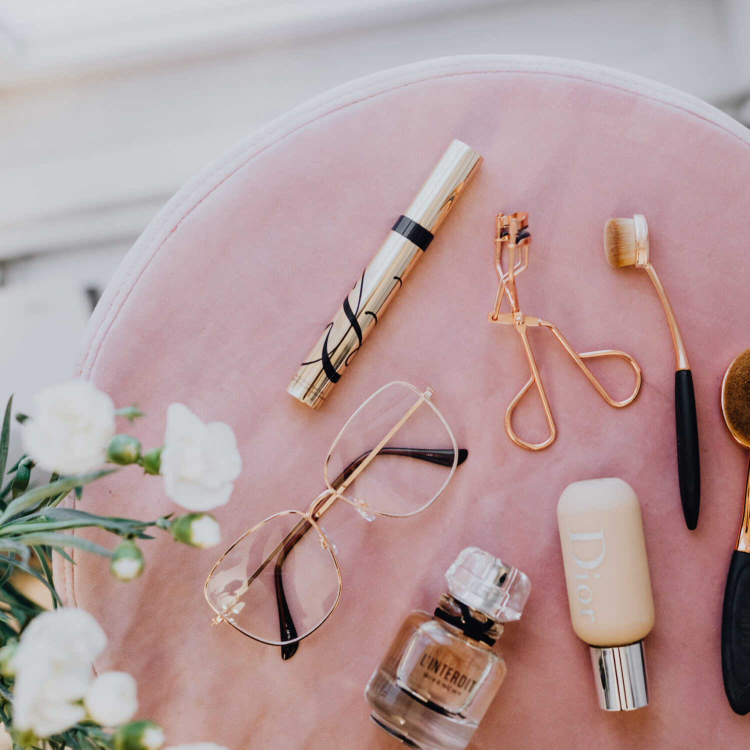 kaboompics_Makeup brushes, eyelash curler & a bottle of perfume on pink velvet