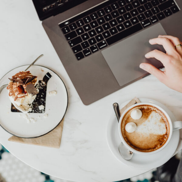 kaboompics_Working with a laptop, meringue with whipped cream and coffee on white marble